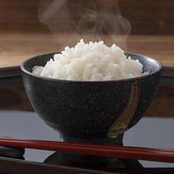 A close-up photograph of freshly harvested rice grains arranged in a bowl